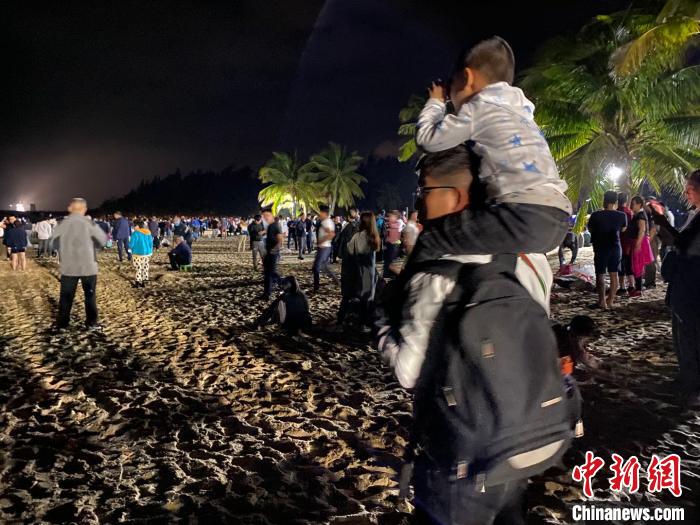 一位兒童坐著父親的肩上用望遠(yuǎn)鏡觀看文昌航天發(fā)射場。凌楠 攝