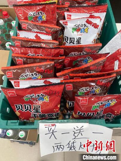 便利店內，因臨期進行“買一送一”促銷的零食?！⌒戽?攝